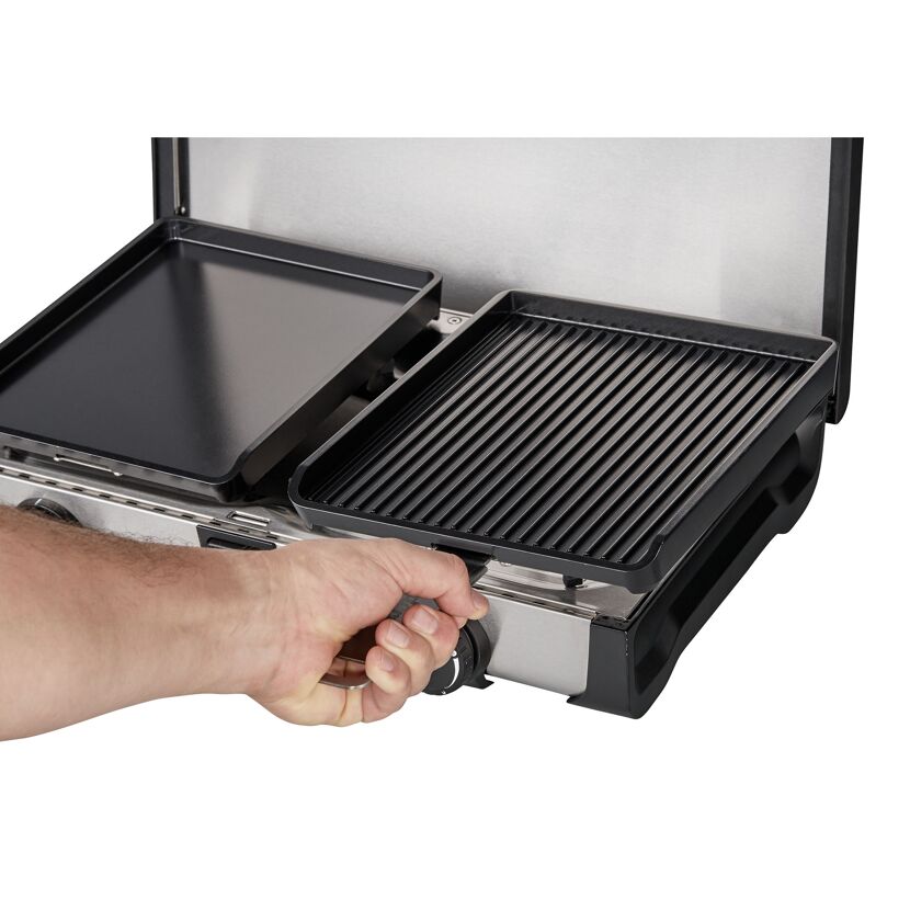 Person stellt Grillplatte auf Campingkocher