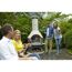 Vier Personen stoßen mit Weingläsern an einem Grillkamin an.
