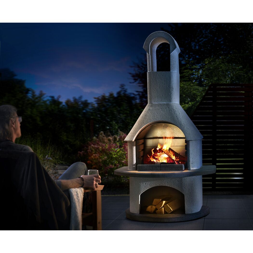 Person sitzt vor brennendem Grillkamin Valenzia