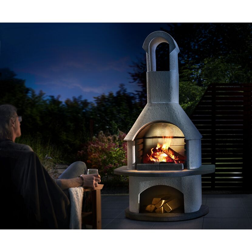 Person sitzt vor brennendem Grillkamin Valenzia