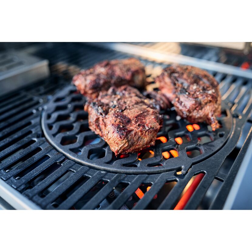 Drei Steaks brutzeln auf einem Grill.
