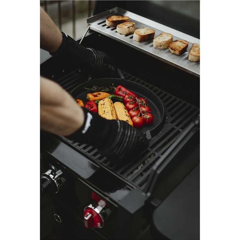 Person legt Gemüse auf Grill