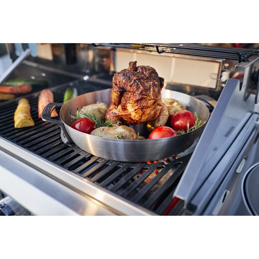 Hähnchen mit Kartoffeln und Tomaten auf einem Grill.
