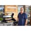Person mit Pizzaschneider am Gasgrill