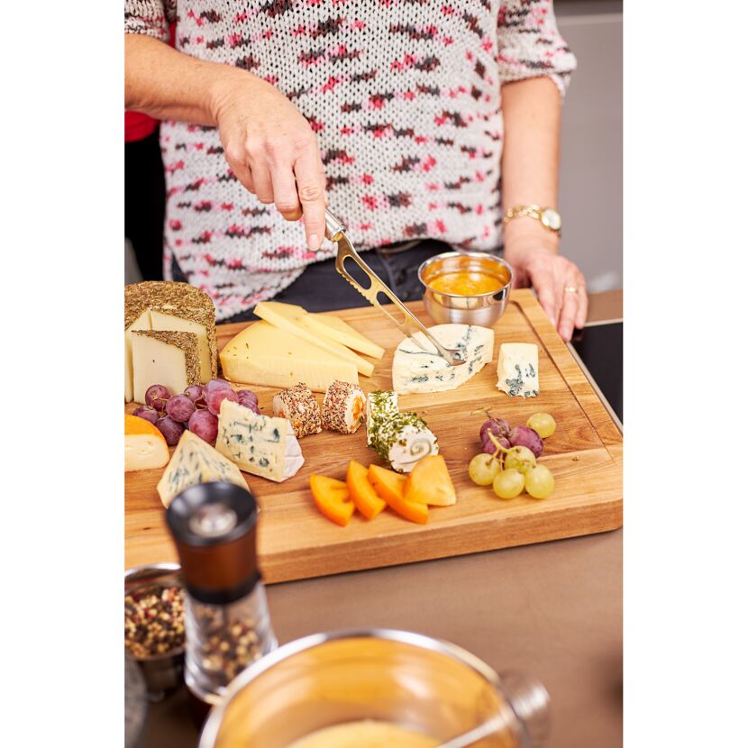 Person schneidet Käse mit Käsemesser