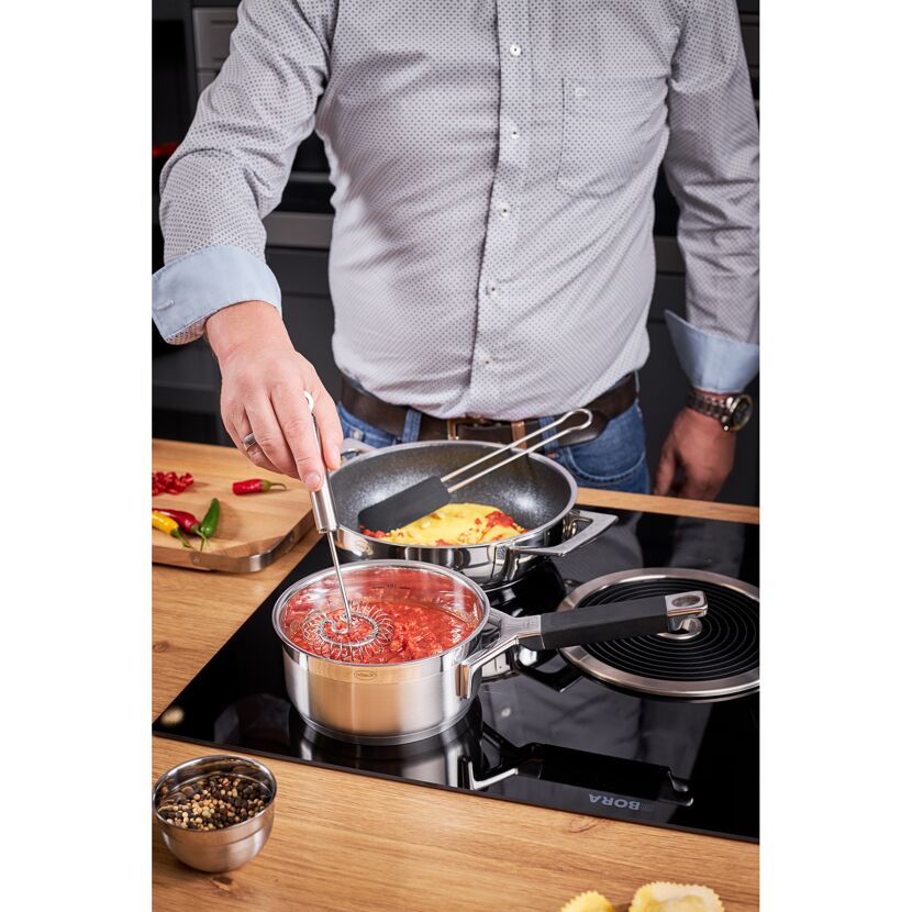 Person verrührt Tomatensoße mit einem Spiralbesen.
