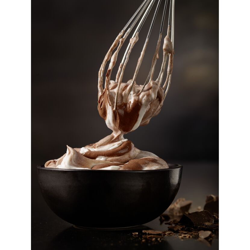 Schneebesen mit Schokoladencreme über einer Schüssel