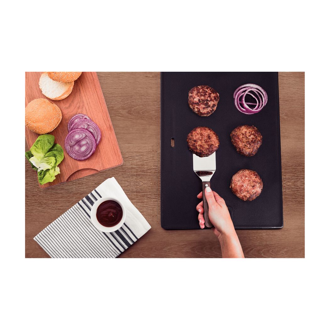 Person wendet Burger-Patties mit einem Grillwender