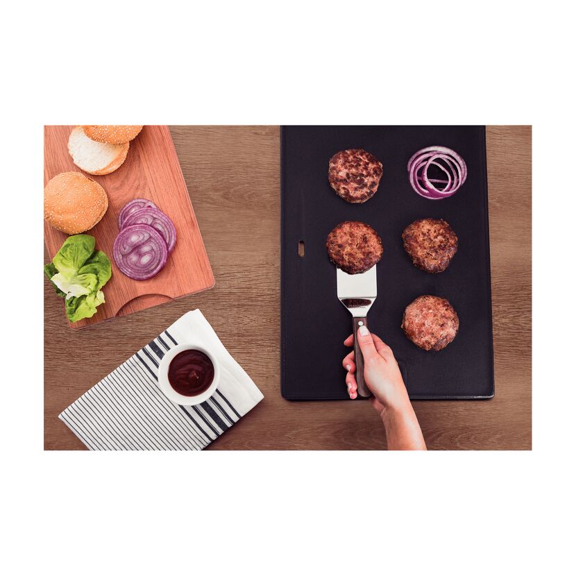 Person wendet Burger-Patties mit einem Grillwender