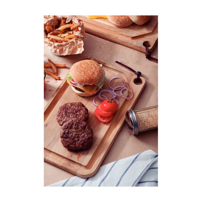 Burger, Pommes und Zutaten auf einem Holzbrett.