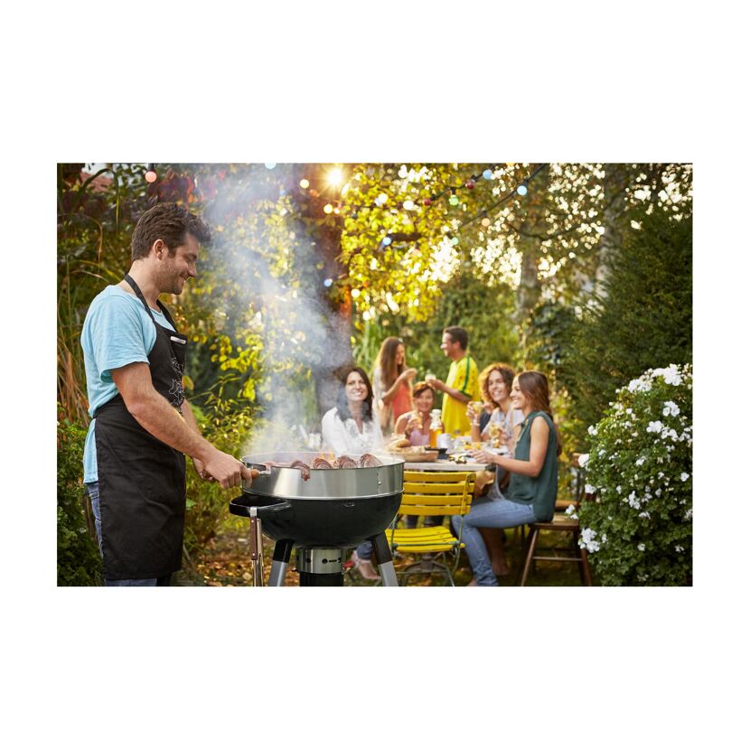 Person grillt für eine Gruppe im Garten