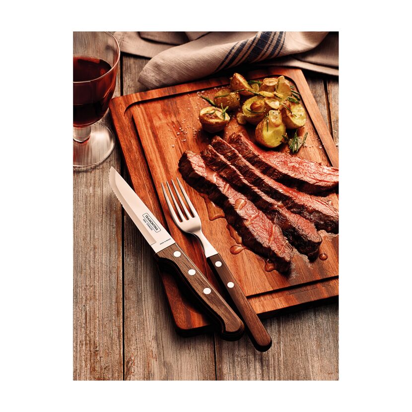 Steakmesser und Gabel neben gebratenem Steak und Kartoffeln