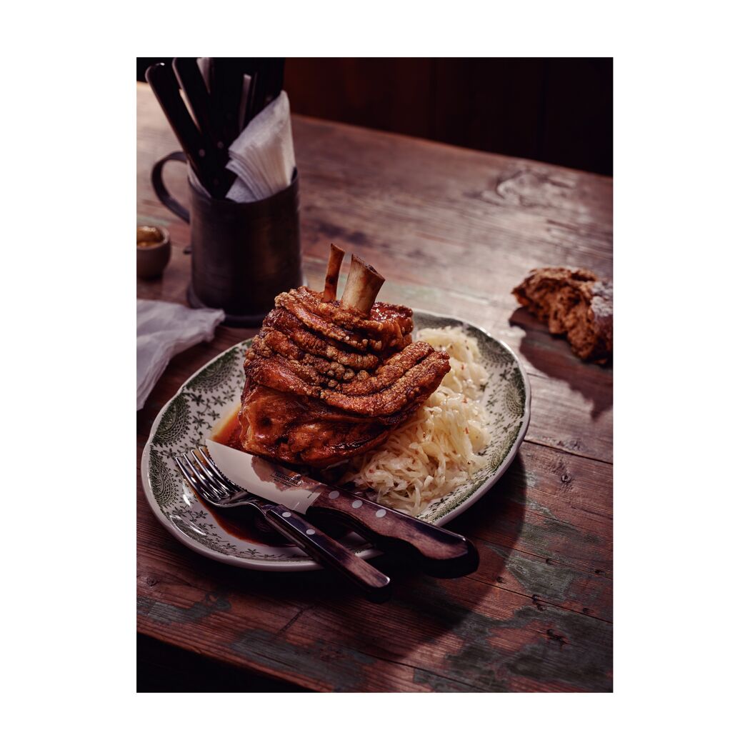 Gebratene Schweinshaxe mit Sauerkraut auf einem Teller.