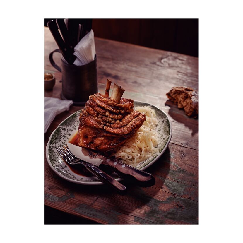 Gebratene Schweinshaxe mit Sauerkraut auf einem Teller.