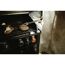 Person grillt Steaks mit Grillgabel auf Gasgrill