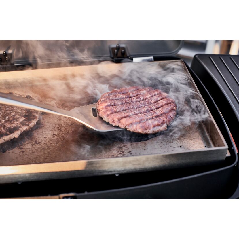 Burger wird mit einem Grillwender gewendet
