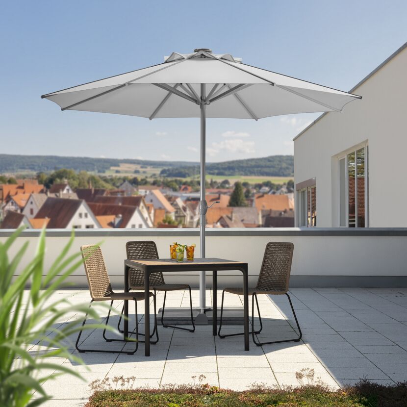 Tisch mit Stühlen und Sonnenschirm auf einer Dachterrasse