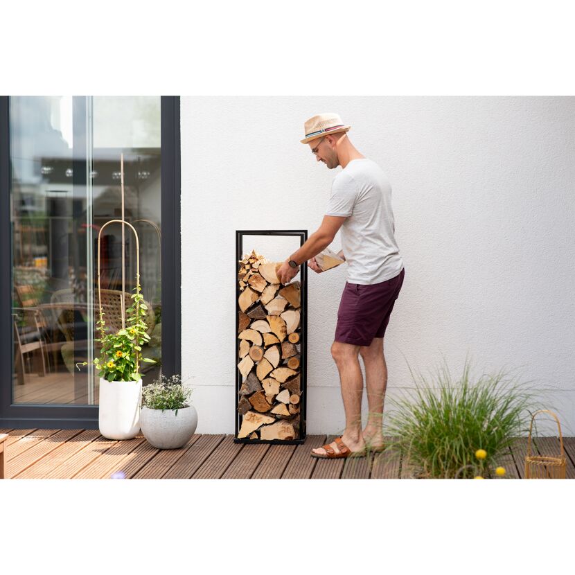 Person stapelt Holzscheite in ein Regal