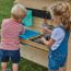 Zwei Kinder spielen mit einer Spielküche im Garten.