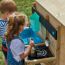 Zwei Kinder spielen mit einer Spielküche im Freien.