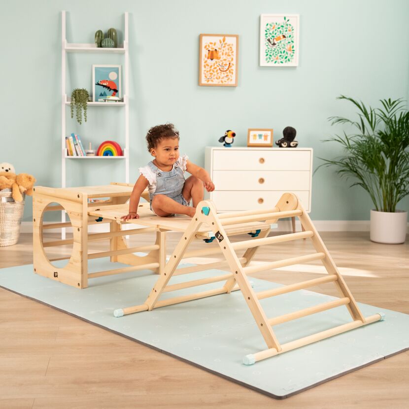 Kleinkind sitzt auf einem Spielgerät aus Holz.