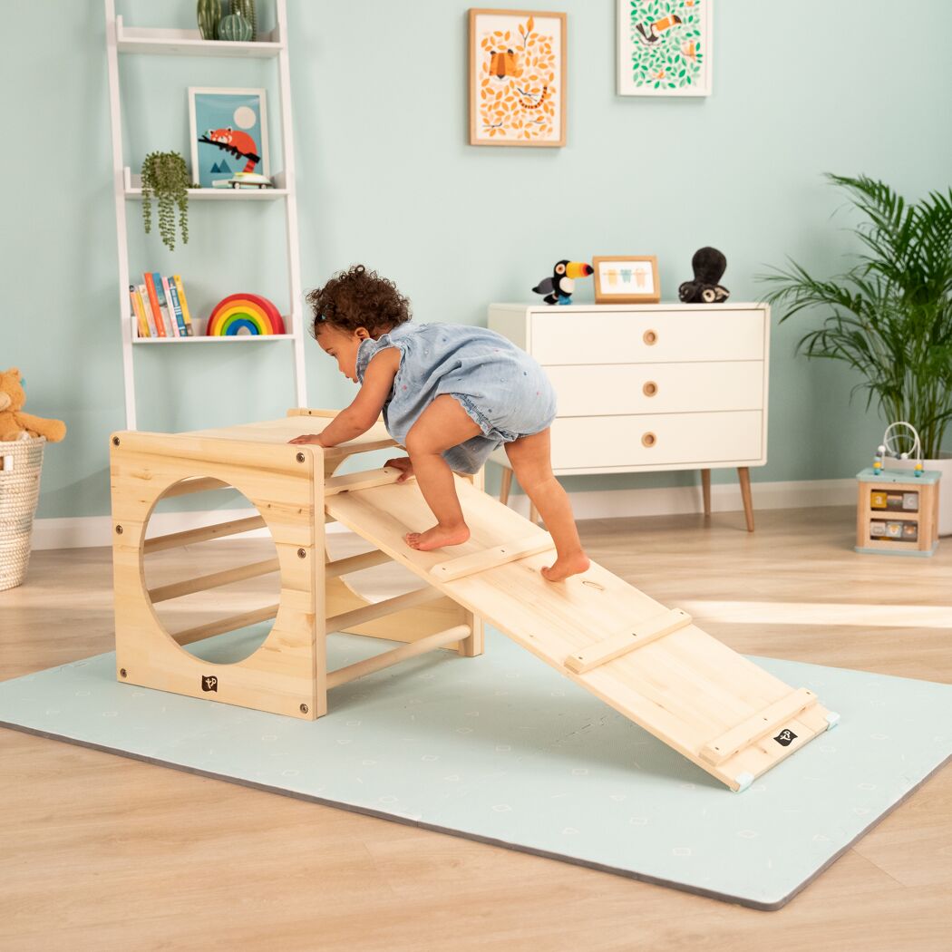Kleinkind klettert auf Spielzeug-Rutsche aus Holz.