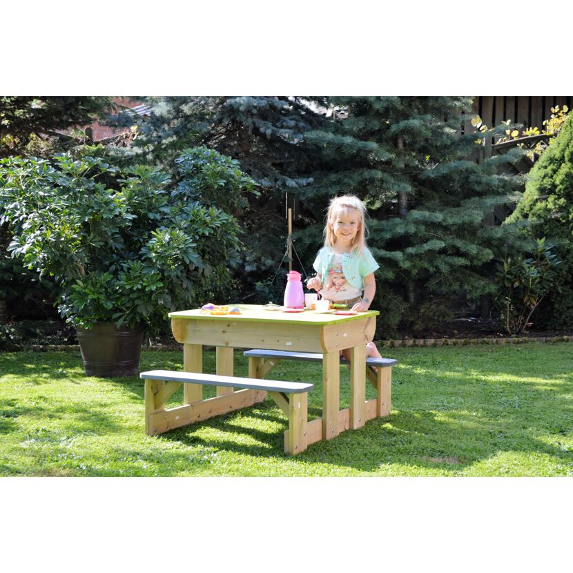 Kind sitzt an einem Picknicktisch im Garten