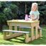 Kind sitzt an einem Sand- und Wassertisch im Garten.