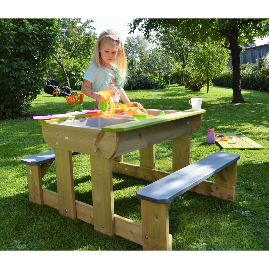Kind spielt mit Sandspielzeug an einem Sand- und Wassertisch im Garten.