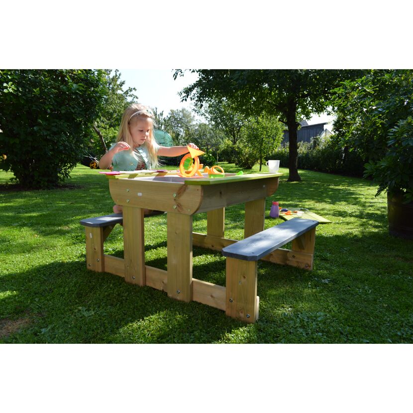 Kind spielt an einem Sand- und Wassertisch im Garten