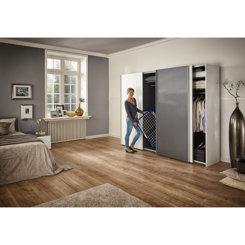 Person holt einen Wäscheständer aus einem Kleiderschrank.
