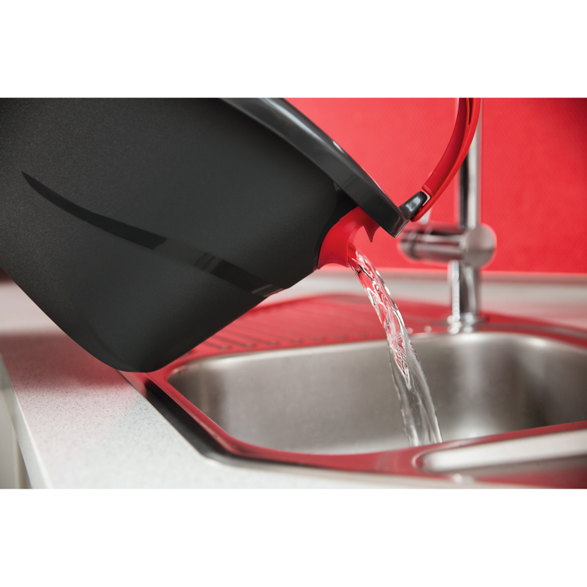 Wasser wird aus einem Eimer in ein Spülbecken gegossen.