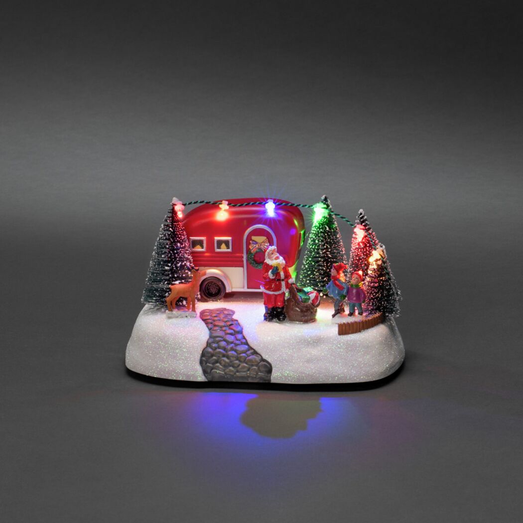 Weihnachtliche Szene mit Wohnwagen, Weihnachtsmann und Kindern.