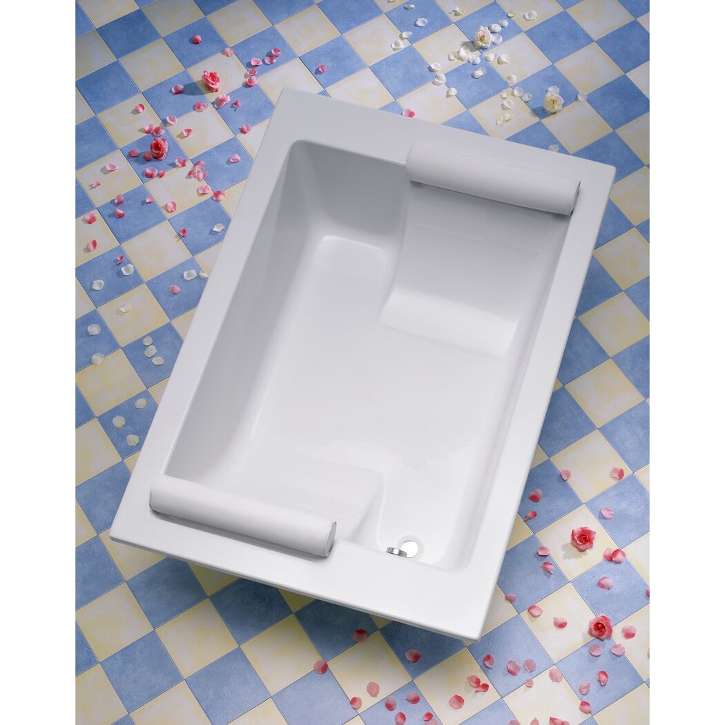 Weiße Badewanne mit zwei Nackenrollen und Rosenblättern