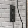 Schwarze Duscharmatur an weißer gekachelter Wand