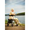 Person sitzt auf Rollator am Flussufer.