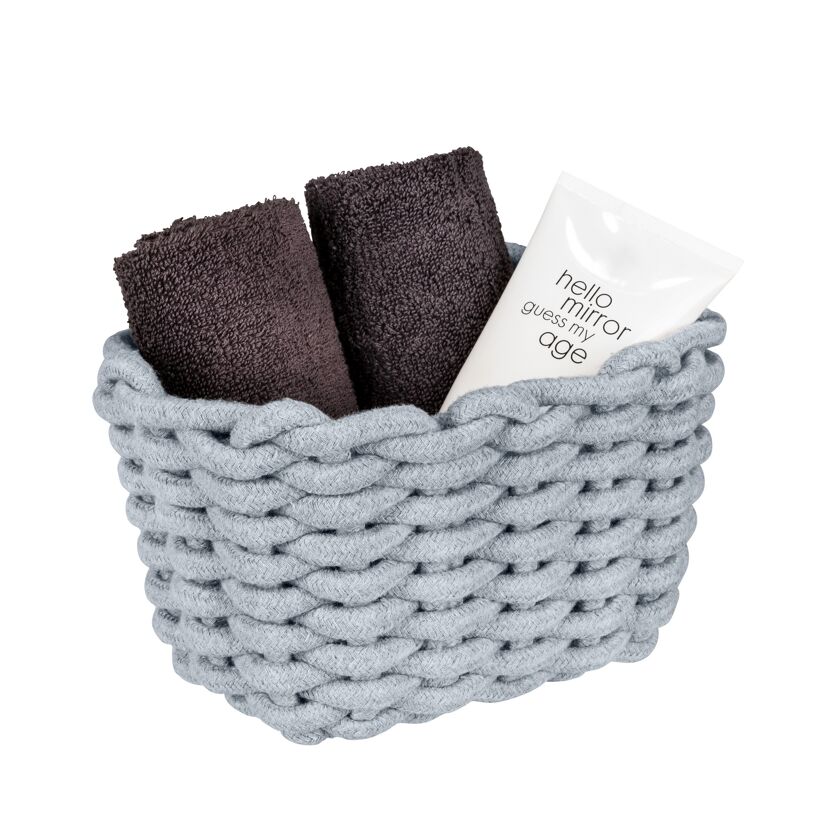 Grauer Korb mit zwei Handtüchern und einer Tube Creme