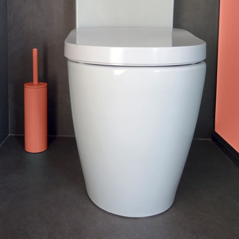 Weiße Toilette mit Toilettenbürste in Terrakotta