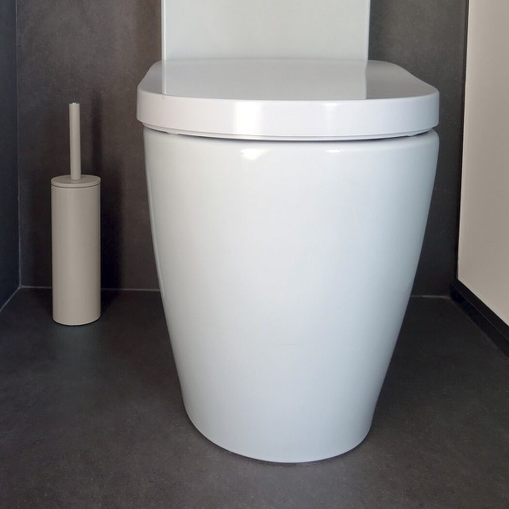Weiße Toilette mit Toilettenbürste daneben.