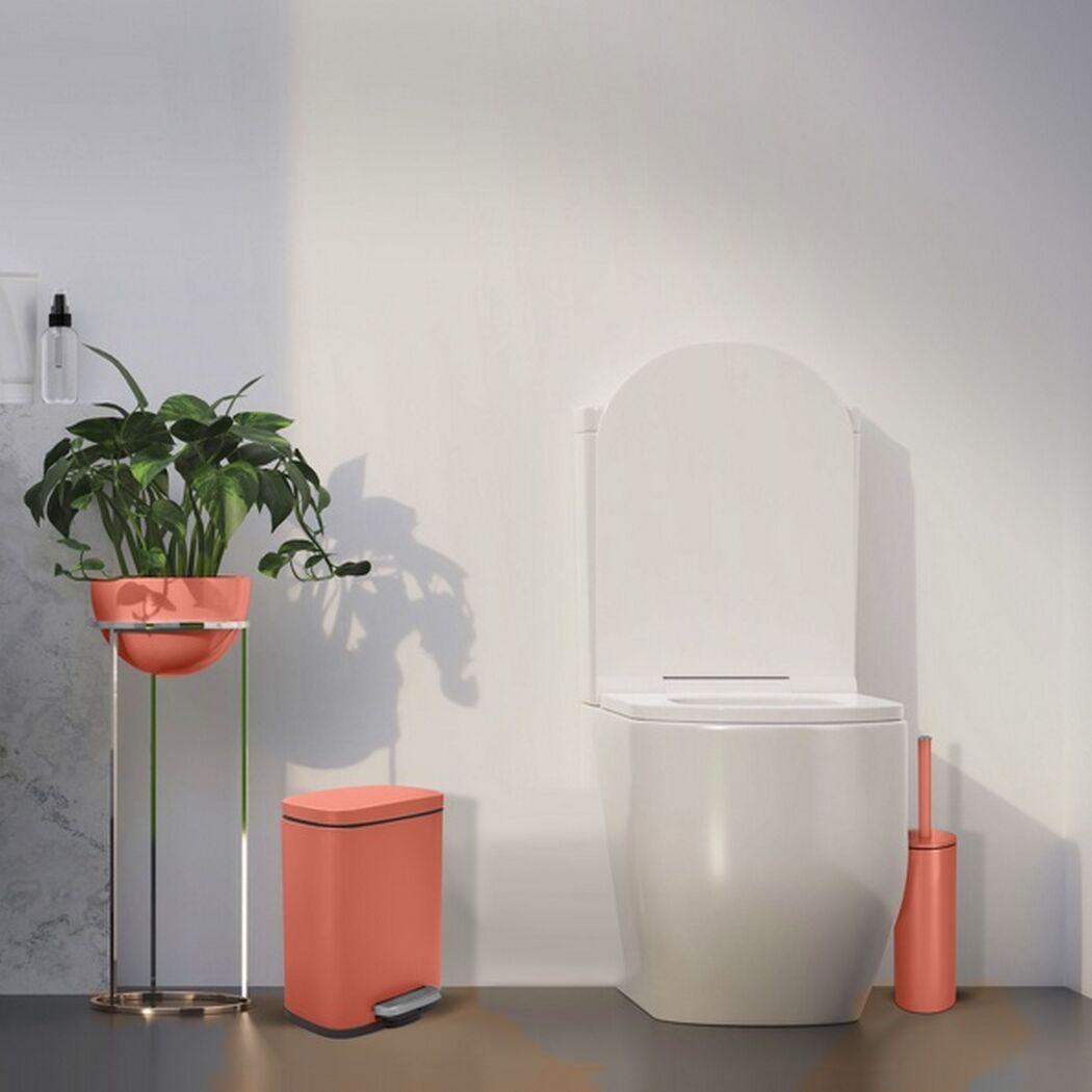 Weißes WC mit korallfarbenem Treteimer und Toilettenbürste