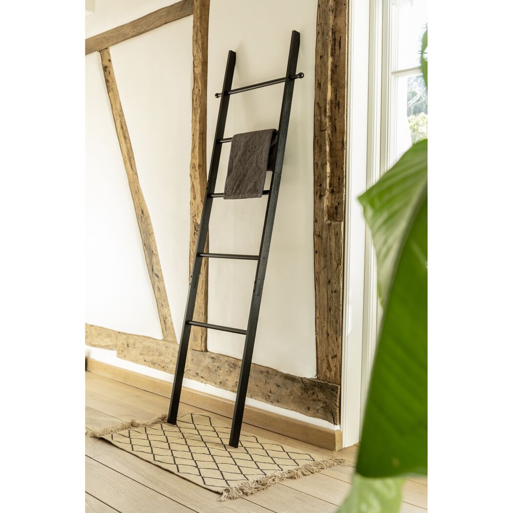 Schwarze Handtuchleiter an einer Wand lehnend.