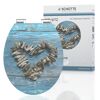 WC-Sitz mit Muschelherz auf blauem Holzhintergrund.