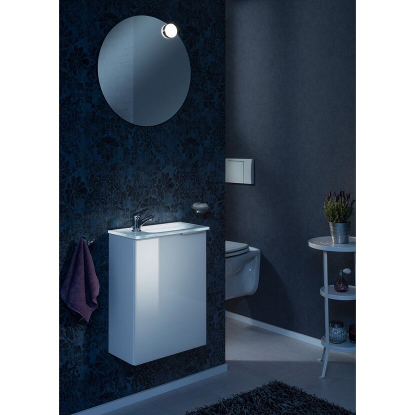 Badezimmer mit rundem Spiegel, Waschbeckenunterschrank und WC