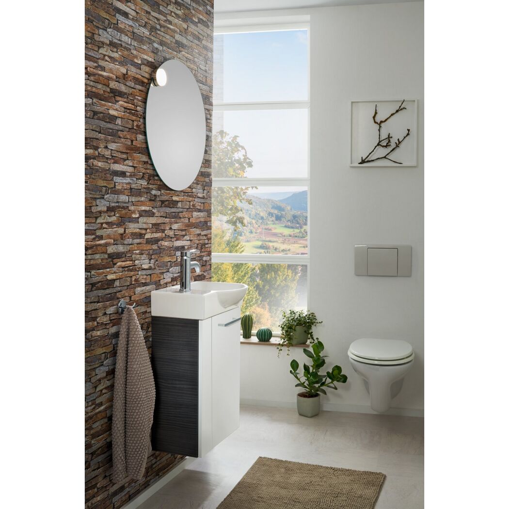 Modernes Badezimmer mit rundem Spiegel, Waschbeckenunterschrank und WC.
