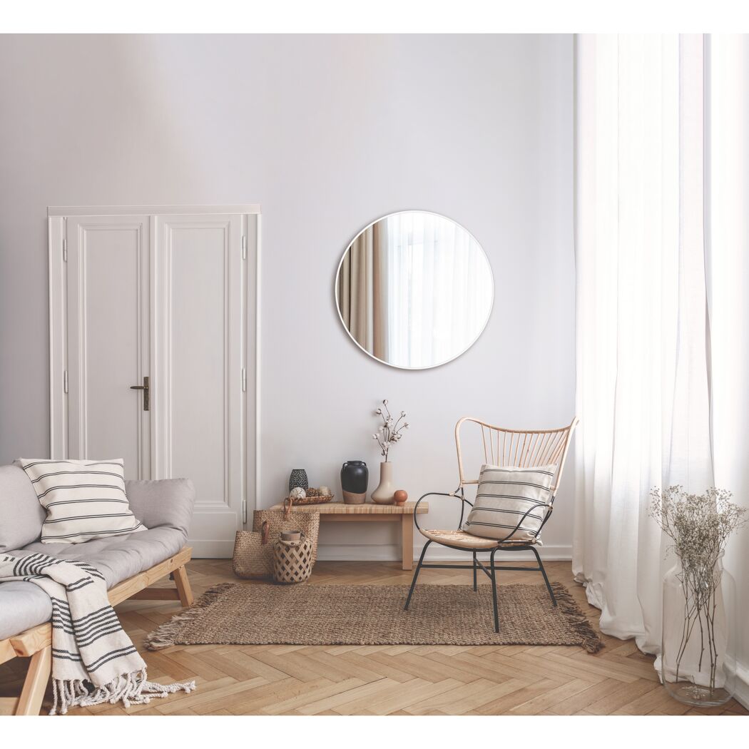 Wohnzimmer mit rundem Spiegel und Korbsessel