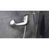 Chromfarbene Brausearmatur an grauer Wand