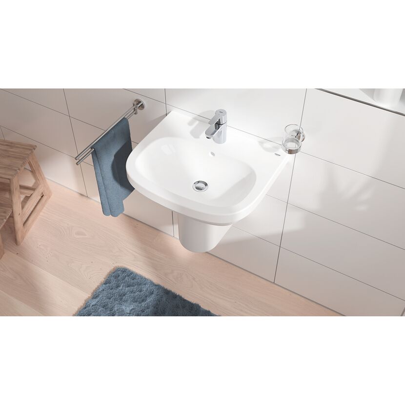 Weißes Waschbecken mit Handtuchhalter und Zahnputzbecher.