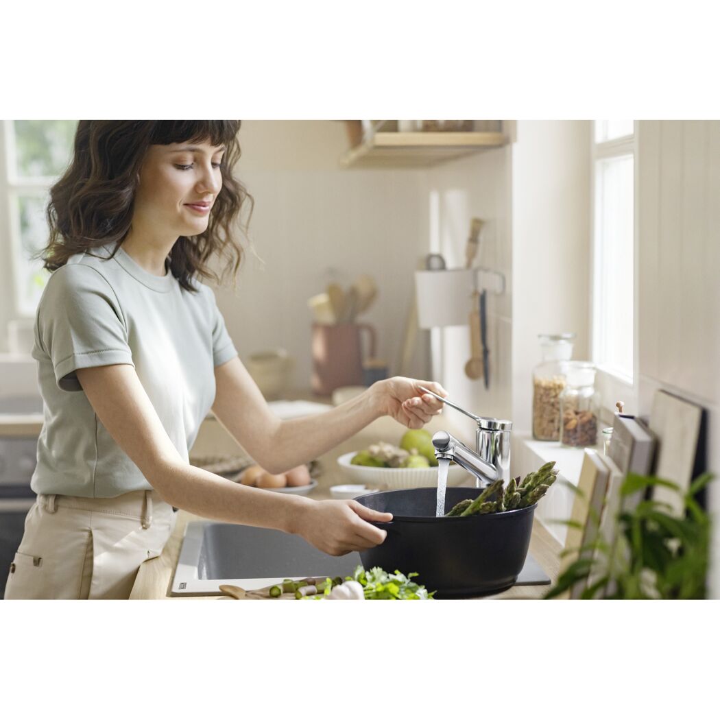 Person füllt Wasser in einen Topf mit Spargel.