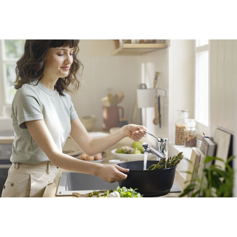 Person füllt Wasser in einen Topf mit Spargel.