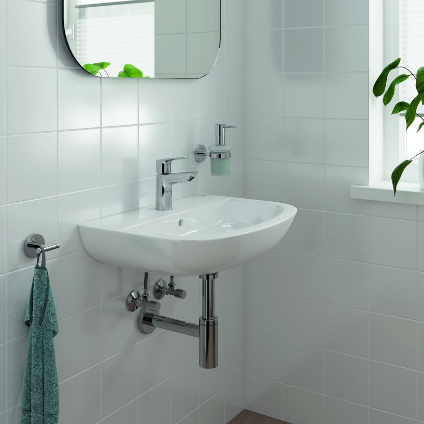 Waschbecken mit Armatur, Handtuch und Seifenspender.